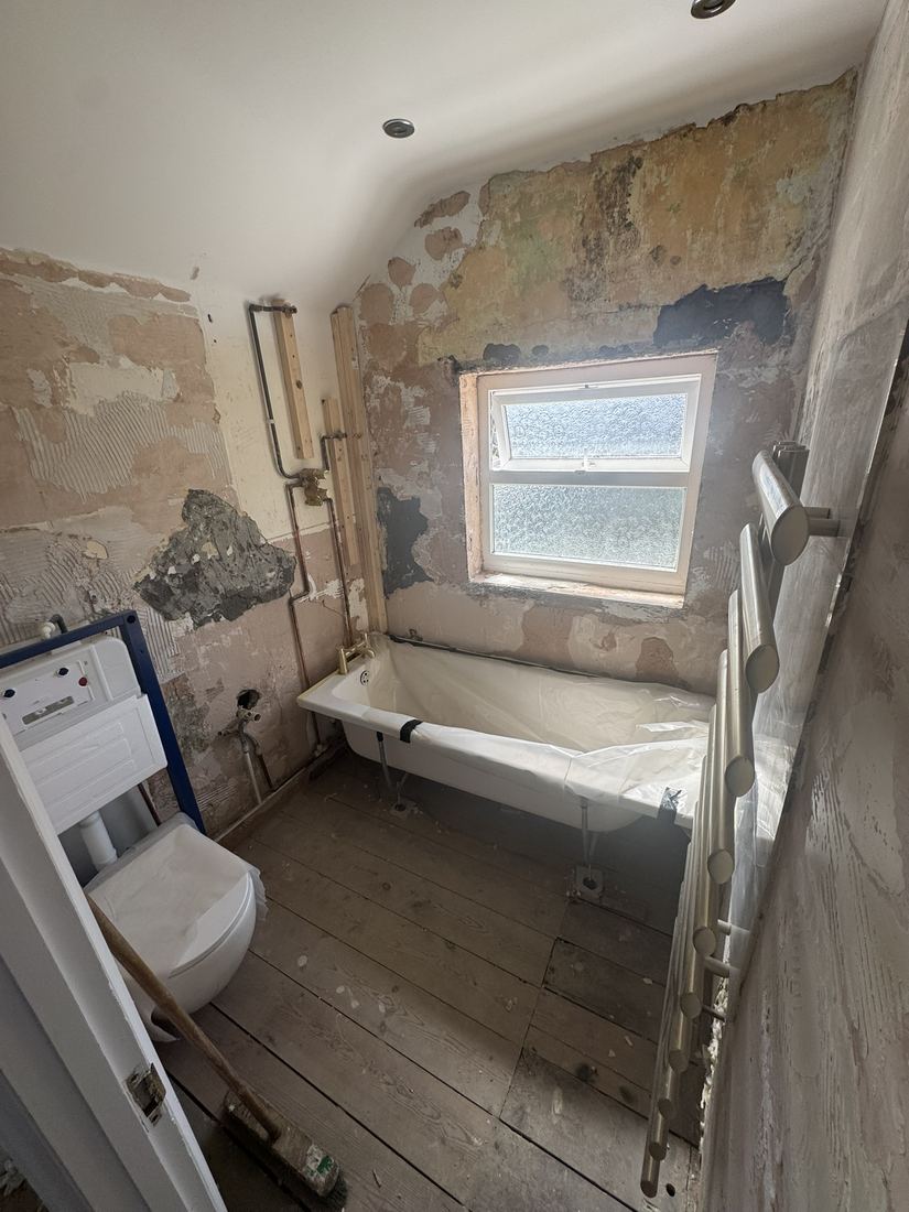 Bathroom before: bare walls and old floorboards
