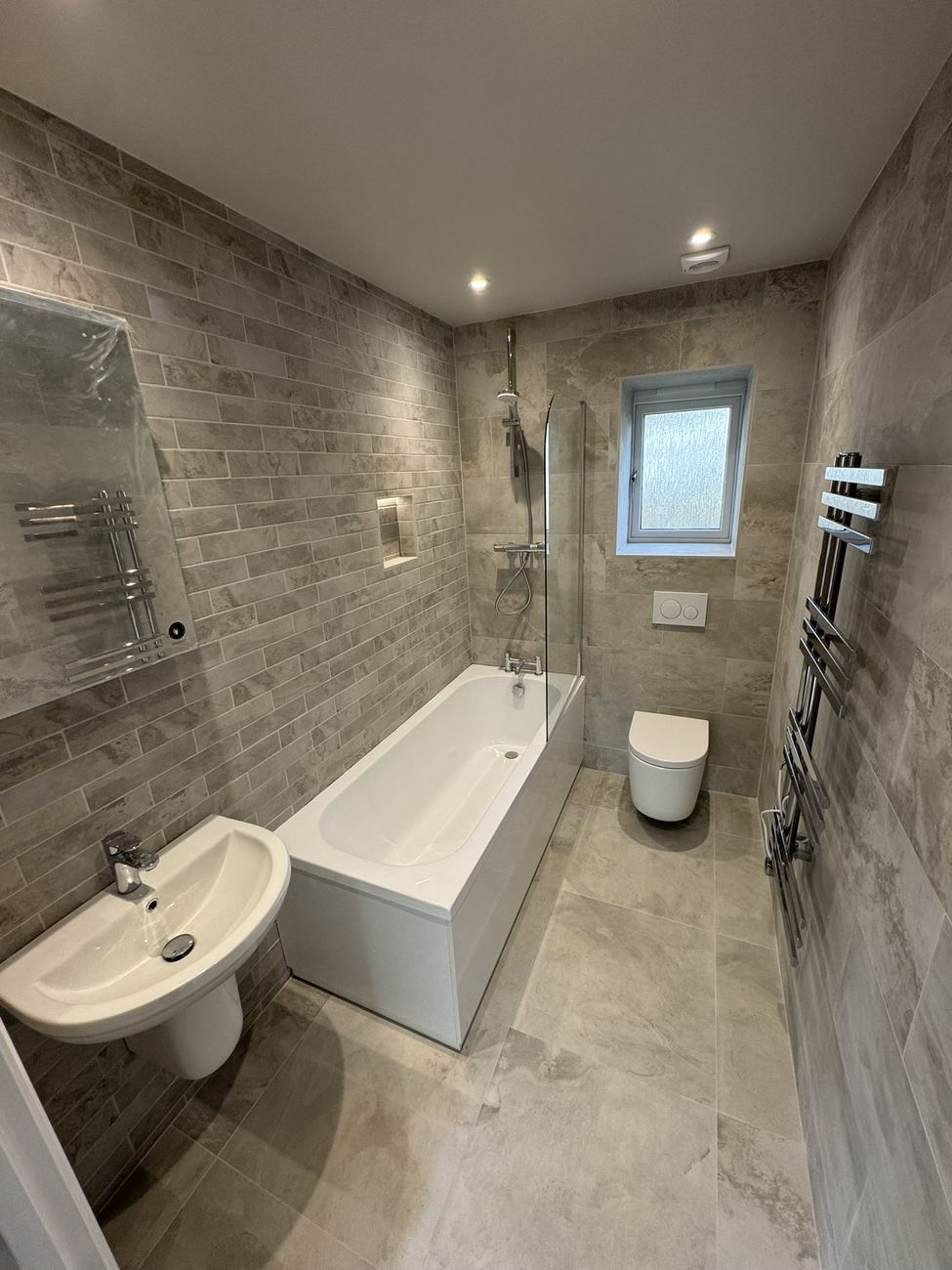 Grey tiled bathroom with heated towel rails